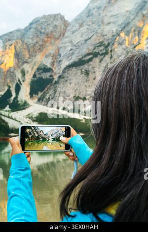 Portraitfrau Wanderer macht Smartphone-Foto vom Pragser Bergsee türkisfarbenes Wasser reflektiert Dolomiten Italien Stockfoto