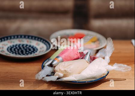 Kuchen, der Paspelsäcke mit bunten Zuckerguss für die Backwerkstatt dekoriert Stockfoto