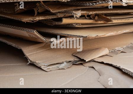 Nahaufnahme von aufgerissenen und zerkleinerten Wellpappenbögen, die übereinander gestapelt sind. Stockfoto