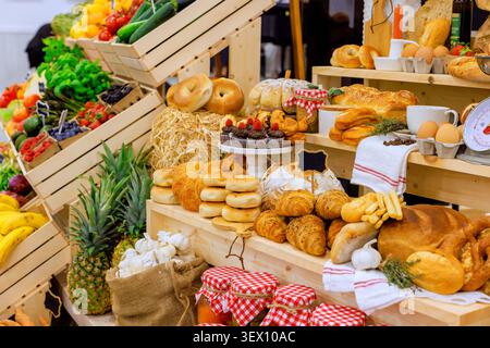 Frisches Obst, Gemüse und Backwaren werden auf Holzregalen auf dem geschäftigen Bauernmarkt angeboten Stockfoto