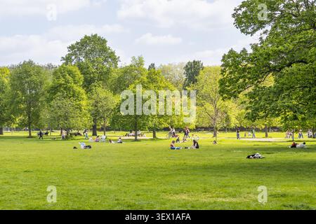 Menschen, die sich auf dem grünen Gras im Hyde Park, London, entspannen Stockfoto