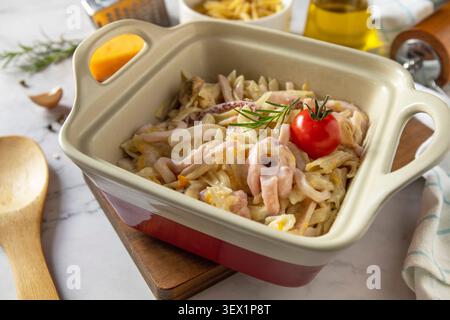 Herzhafte hausgemachte Penne-Pasta mit Meeresfrüchten in cremiger Käsesauce auf Marmorarbeitsfläche. Stockfoto