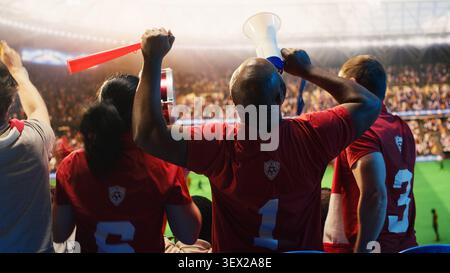 Nahaufnahme von fröhlichen Fußballfans, die sich auf Stadiontribünen tummeln, begeistert vom Tor in letzter Minute. Emotionale Fußballfans umarmen sich nach dem Sieg von der Lieblingsmannschaft Stockfoto