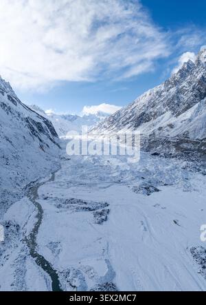 Aus der Vogelperspektive auf den Arandu-Gletscher, umgeben von schneebedeckten Bergen und einem sich windenden Gletscherfluss unter einem hellblauen Himmel in Shigar, Gilgit Baltistan, Pa Stockfoto