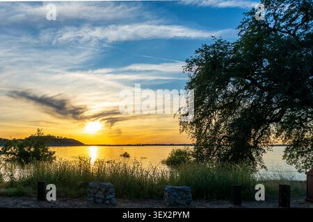 Frühling Sonnenuntergang über Calm Lake Waters und Fern Hills am Folsom Lake, Kalifornien Stockfoto