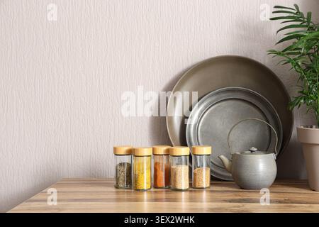 Küchentisch mit Gewürzgläsern, Teekanne, Tellern und Pflanzen Stockfoto