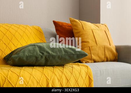Farbenfrohe dekorative Kissen auf grauem Sofa mit gelbem Überwurf Stockfoto