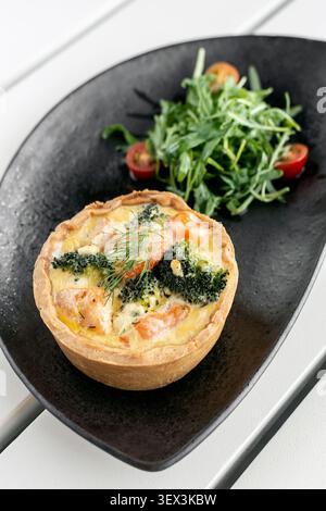 Lachs und Brokkoli Quiche mit Salat gesunde Mahlzeit auf weißem Kaffeetisch auf ibiza Stockfoto