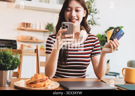 Glück Unternehmer schönes Geschäft asiatische junge Frau tragen lässig Handy zum Einkaufen online genießen Sie mit sozialen Medien und Laptop zu Hause Stockfoto