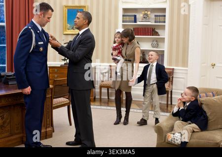 Mitglieder der Price-Familie sehen, wie Präsident Barack Obama am 9. Januar 2012 im Oval Office die Defense Superior Service Medal an den abscheidenden Militärhelfer Sam Price überreicht. (Offizielles Foto des Weißen Hauses von Pete Souza) dieses offizielle Foto des Weißen Hauses wird nur für die Veröffentlichung durch Nachrichtenorganisationen und/oder für den persönlichen Gebrauch durch den/die Gegenstand(e) des Fotos zur Verfügung gestellt. Das Foto darf in keiner Weise manipuliert und nicht in kommerziellen oder politischen Materialien, Anzeigen, E-Mails, Produkten oder Werbeaktionen verwendet werden, die auf irgendeine Weise eine Genehmigung oder Billigung nahelegen Stockfoto