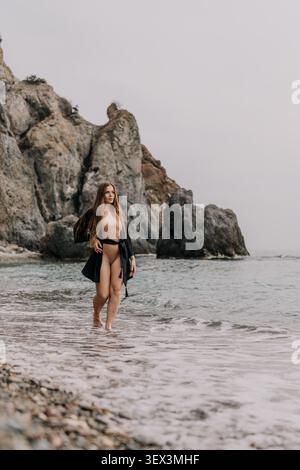 Woman Beach Rocks spazieren Sie an einem bewölkten Morgen entlang der Küste einer malerischen felsigen Küste mit viel Platz zum Kopieren Stockfoto