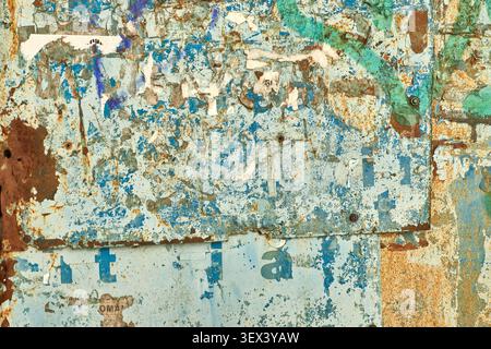 Vollbild-Nahaufnahme eines alten, verwitterten blauen Metallpinnentafels mit rostigen Flecken, abblätternder Farbe und gerissenen Papierresten. Grungy strukturiert Stockfoto