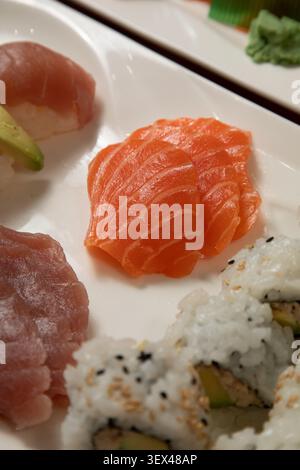 Des morceaux de sashimi de saumon sont présentés sur une assiette avec des sushis. Stockfoto