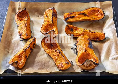 Geröstete Butternusskürbis-Hälften auf Pergamentpapier auf einem Backblech, nicht künstliche Intelligenz Stockfoto