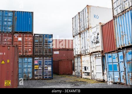 Alte, abgenutzte Schiffscontainer stapelten sich im Handelshafen in Reykjavík, Island, die industrielle Lagerung und Seehandel zeigen. Stockfoto