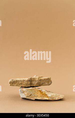 Rohe Natursteine, die übereinander balanciert sind, sorgen für eine minimalistische Produktpräsentation vor neutralem Hintergrund. Sockel aus Naturmaterial Stockfoto