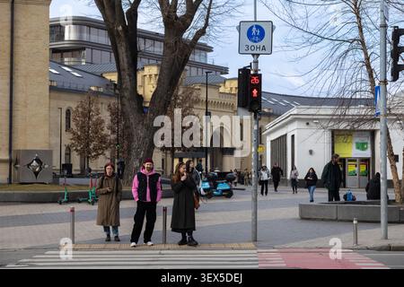 Kiew, Ukraine - 21. März 2026: Fußgänger stehen während eines ruhigen Nachmittags in einer modernen Stadt auf einem Bürgersteig und warten auf Ampeln in der Nähe des historischen Ar Stockfoto