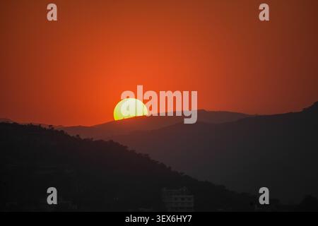 Sonnenuntergang hinter dem Bergrücken mit dramatischem orangenem Himmel Stockfoto