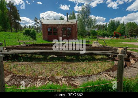 Historische Eisenbahndrehscheibe am alten Bahnhofsbahnhof Porvoo in Finnland. Im Hintergrund steht ein rustikales, rotes Backsteinmotorenhaus, umgeben von Grün Stockfoto