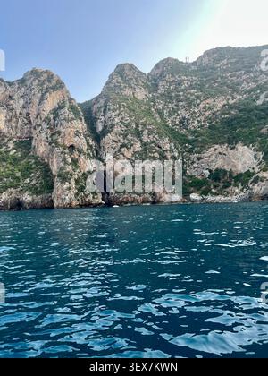 Malerischer Blick vom Mittelmeer auf die massiven felsigen Klippen des Mount Gouraya Nationalparks mit einem natürlichen Meereshöhleneingang, Bejaia, Algerien. Stockfoto