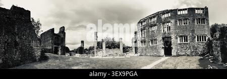 Offener Bereich umgeben von Ruinen mit Säulen und zerbröckelnden Mauern unter einem bewölkten Himmel, Berry Pomeroy Castle, Devon, England, Großbritannien Stockfoto