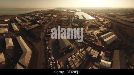 Luftaufnahme eines Industriegebiets mit Lagerhäusern und Versandcontainern nahe der Küste bei Sonnenuntergang, Cardiff Docks, Großbritannien Stockfoto