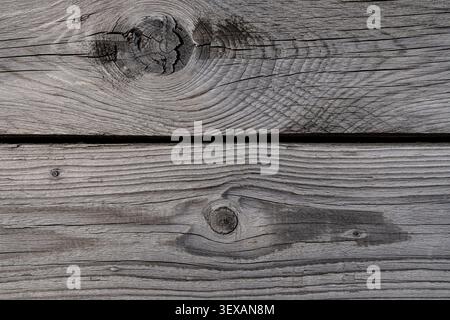 Nahaufnahme verwitterter grauer Holzdielen mit einem markanten Knoten. Stockfoto