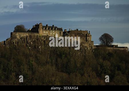 Stirling Castle in Schottland verfügt über eine Burg auf einem Hügel, felsige Hänge und dunkle Bäume, mit Bäumen bewachsene Hänge, die Größe und ein klares Gefühl von Ort verleihen. Stockfoto