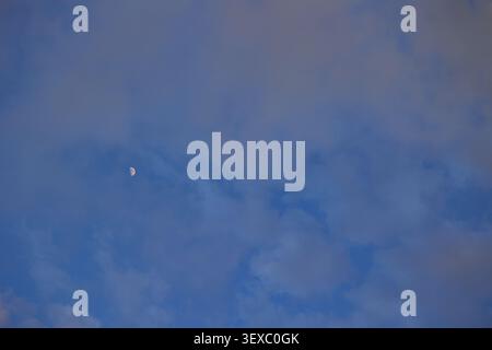 Mond am bewölkten Himmel vor Sonnenuntergang. Stockfoto