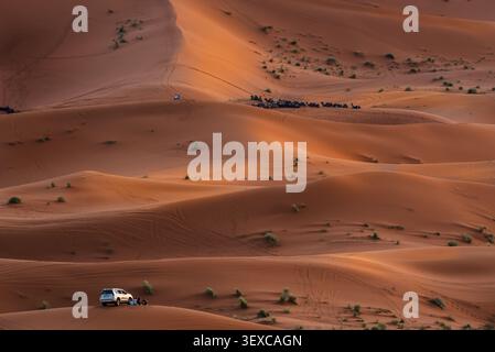 Die Merzouga-Dünen, Marokko. Zwei Reisearten – Jeep und Kamele – in den Merzouga-Dünen der Sahara, Marokko. Stockfoto