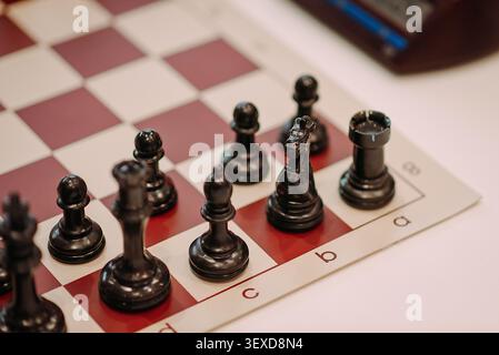 Schwarze Schachfiguren auf dem Schachbrett nähern sich selektiv Stockfoto