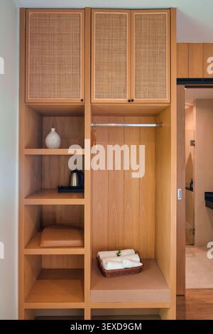 Moderner klassischer Holzschrank mit offenen Regalen, Rattantür, Hängebereich und Gastfreundschaftsobjekt in der Unterkunft Stockfoto