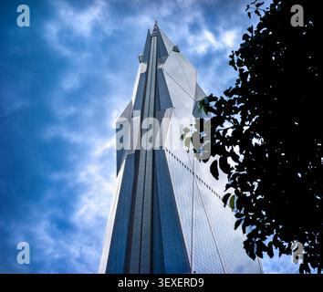 Flacher Blick auf die dramatische, kristalline Fassade des Wolkenkratzers Merdeka 118 unter einem bewölkten blauen Himmel in Kuala Lumpur. Stockfoto