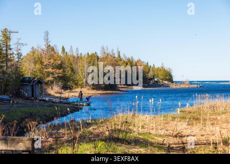 Ruhige Szene des Singing Sand Beach in Tobermory, die einen friedlichen See zeigt, der von üppigen Bäumen unter einem klaren blauen Himmel gesäumt ist. Ideal für Reisen und Natur Stockfoto