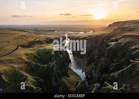 Atemberaubende Drohnenansicht des Fjadrargljufur Canyons in Island bei einem goldenen Sonnenuntergang, der den sich windenden Fluss Fjadra zeigt, der durch steile Mos fließt Stockfoto