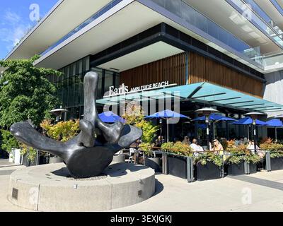 Earls Ambleside Beach Restaurant Terrasse mit einer großen öffentlichen Skulptur vor einem modernen Gebäude am Wasser in West Vancouver, British Columbia, Cana Stockfoto