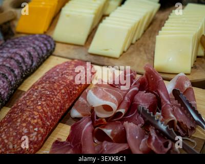 Gourmet-Wurstplatte mit geschnittenem Schinken, Salami und verschiedenen Käsesorten auf Holzplatten aus nächster Nähe Stockfoto