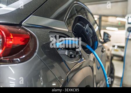 Laden eines Elektrofahrzeugs in einem modernen Parkhaus in den Niederlanden, Nahaufnahme Stockfoto