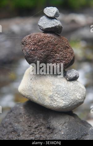 Nahaufnahme eines Zen-Steinstapels, der auf einem Flussbett mit einem weichen, unscharfen Hintergrund balanciert und Harmonie, Achtsamkeit und Stabilität repräsentiert. Stockfoto