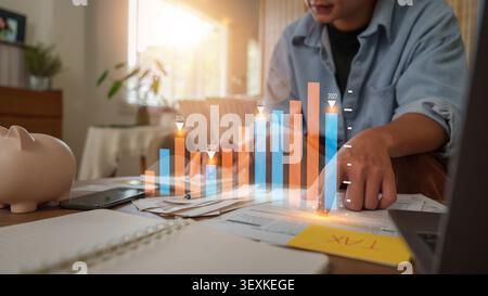 Mann analysiert Finanzdiagramme und Steuerdokumente am Home Desk für die Planung Stockfoto