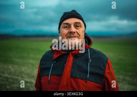 Ein älterer Mann lächelt und trägt warme Kleidung draußen Stockfoto