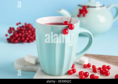 Tasse heißen Viburnum-Tee und Beeren auf blauem Hintergrund Stockfoto