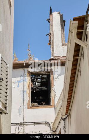 Fenster und Wand des verbrannten Hauses mit zerstörtem Dach nach einem Großbrand. Stockfoto