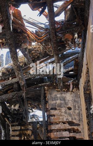 Verkohlte Holzbalken und das Innere des Dachs des verbrannten Hauses nach dem Feuer. Stockfoto