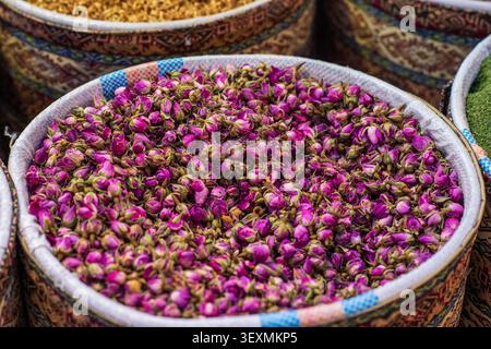 Nahaufnahme eines Korbs, gefüllt mit kleinen getrockneten Rosenknospen in Rosa- und Magenta-Tönen. Die dichte Komposition unterstreicht die natürlichen Details Stockfoto