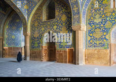 Große Innenhalle mit Steinsäulen und gewölbten Decken, bedeckt mit dichten blauen und gelben Fliesen Mosaiken. Links eine weibliche Figur, die einen Trad trägt Stockfoto