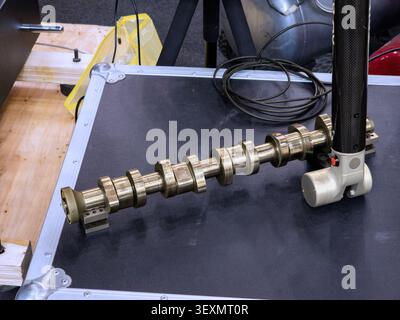 Ein tragbarer Gelenkarm mit Koordinatenmessgerät (CMM) führt eine Präzisionsprüfung einer Motornockenwelle aus Metall zur Qualitätskontrolle in Manufa durch Stockfoto