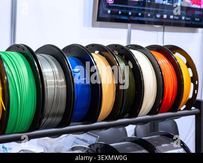 Ein lebendiges Sortiment an mehrfarbigen Kunststofffilamenten-Spulen, einschließlich PLA und ABS, die ordentlich auf einem Display-Rack für 3D-Druck und Prototypin angeordnet sind Stockfoto