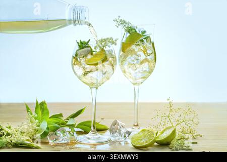 Erfrischendes Sommergetränk namens Hugo Spritz wird in zwei Weingläser gegossen, Cocktail aus Prosecco, Holunderblüten, Sirup, Limonade, Minze- und Zitronenscheiben, LIG Stockfoto