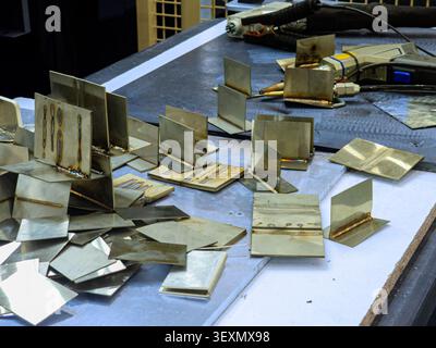 Eine Sammlung von Proben von Schweißnähten aus Edelstahl, die verschiedene Schweißtypen zeigen und bei einer industriellen Arbeit auf einer Werkbank neben einem Schweißbrenner liegen Stockfoto